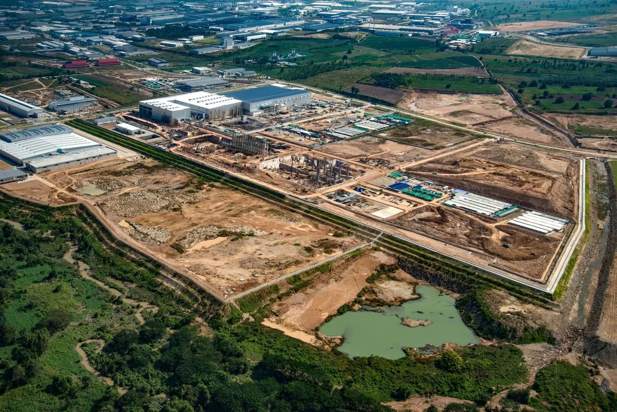 Aerial view of an industrial park under construction, showing graded pads, haul roads and a stormwater pond at the site edge