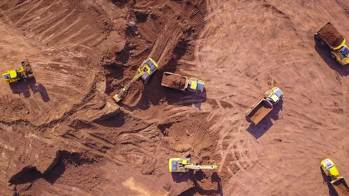 Overhead view of excavators and haul trucks working across cut earth